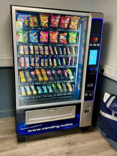 A Crane vending machine filled with snacks and drinks, displaying various brand options.